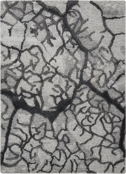 Close-up of gray dried mud with dark jagged fissures and rough surface.