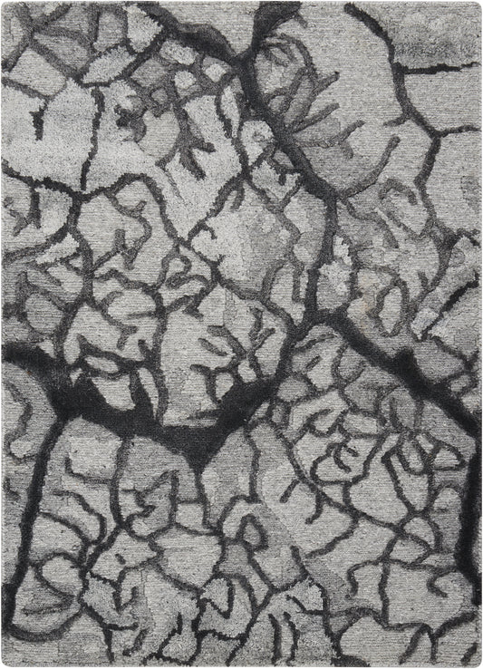 Close-up of gray dried mud with dark jagged fissures and rough surface.