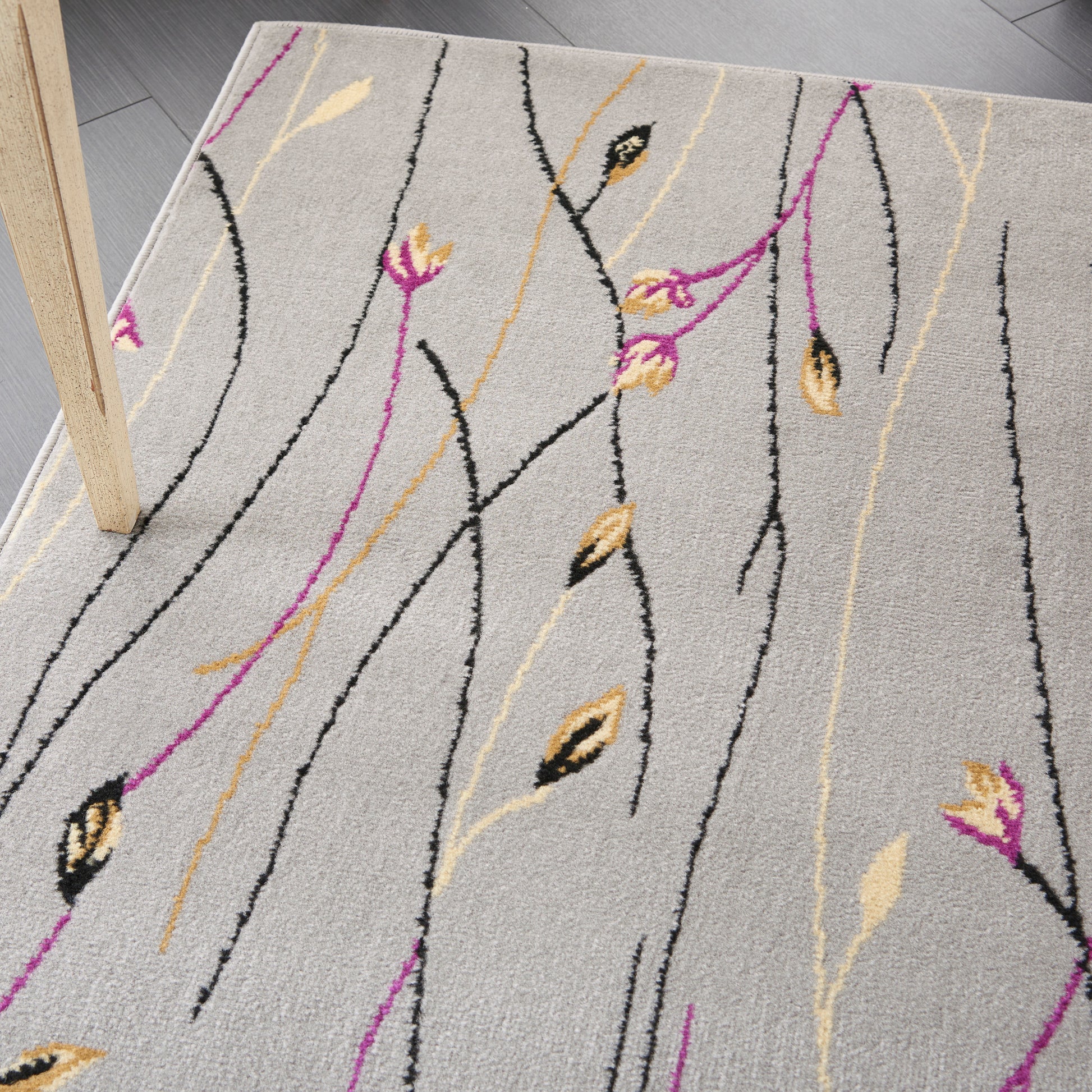 Beige-gray rug with slender black lines and pink and gold vine-like lines with leaf motifs; modern abstract botanical.