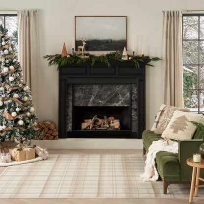 Black marble fireplace with garland, candles; Christmas tree, gifts, green sofa, beige plaid rug in cozy holiday living room.