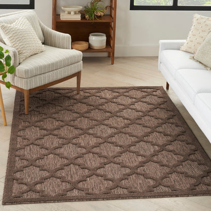Brown geometric trellis rug in a cozy living room with cream armchair, white sofa, and light wood floors.