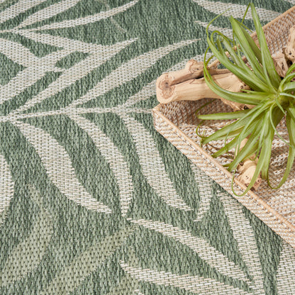 Woven green palm-leaf patterned rug on beige background; natural fiber texture.