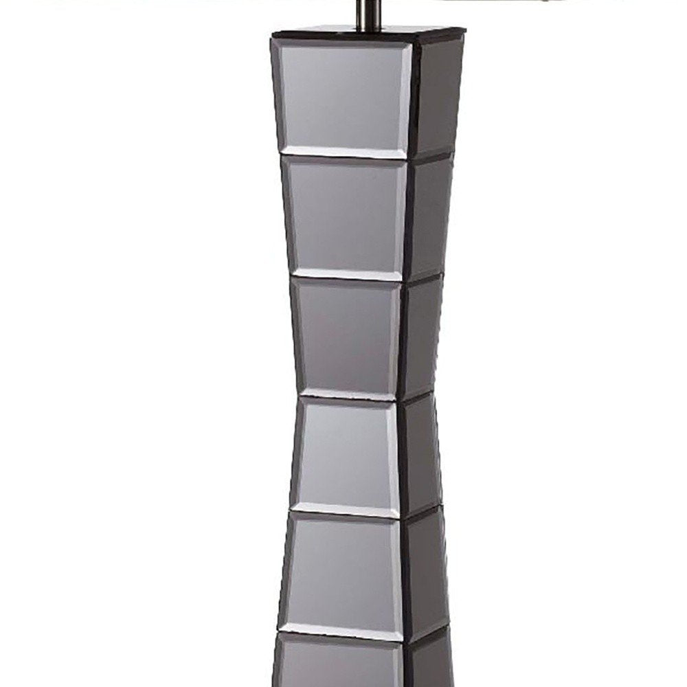 Tall black glass tower table lamp with a beige fabric shade; base features stacked square-panel sections for a modern sculptural look.