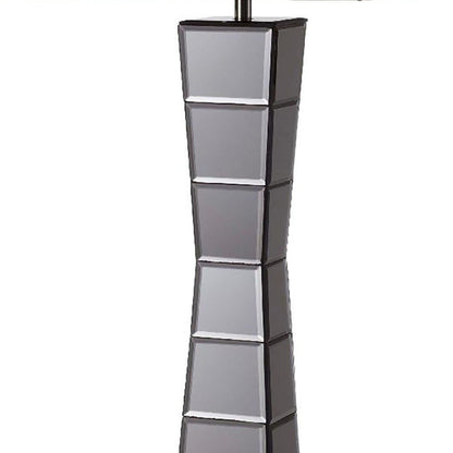Tall black glass tower table lamp with a beige fabric shade; base features stacked square-panel sections for a modern sculptural look.