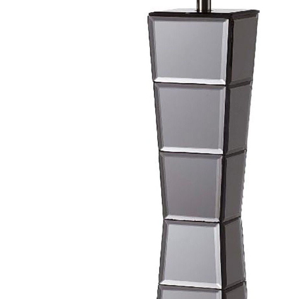 Table lamp with a black glass tower and a beige fabric shade.