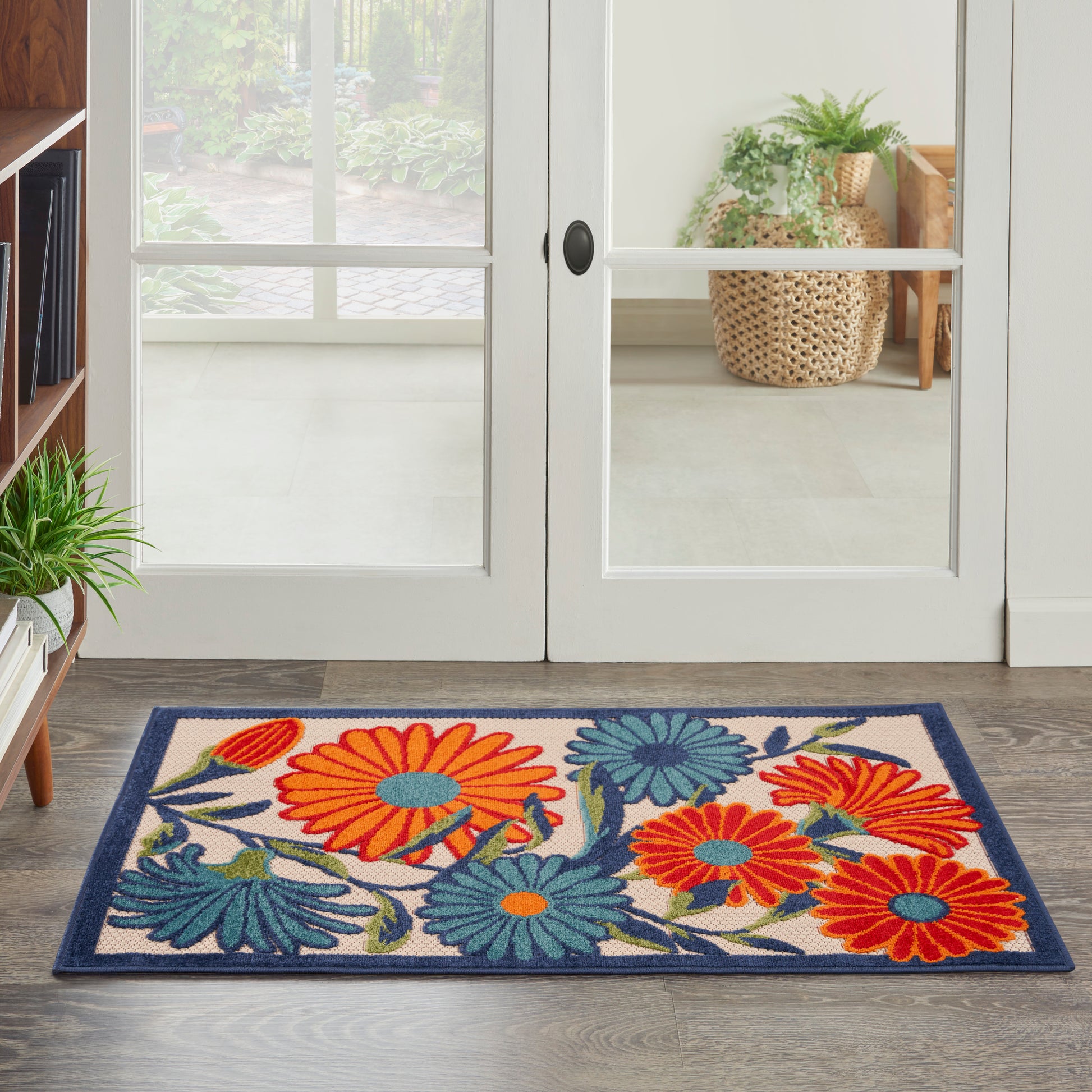 Colorful floral door mat with large orange and blue flowers, teal leaves, beige background and navy border.