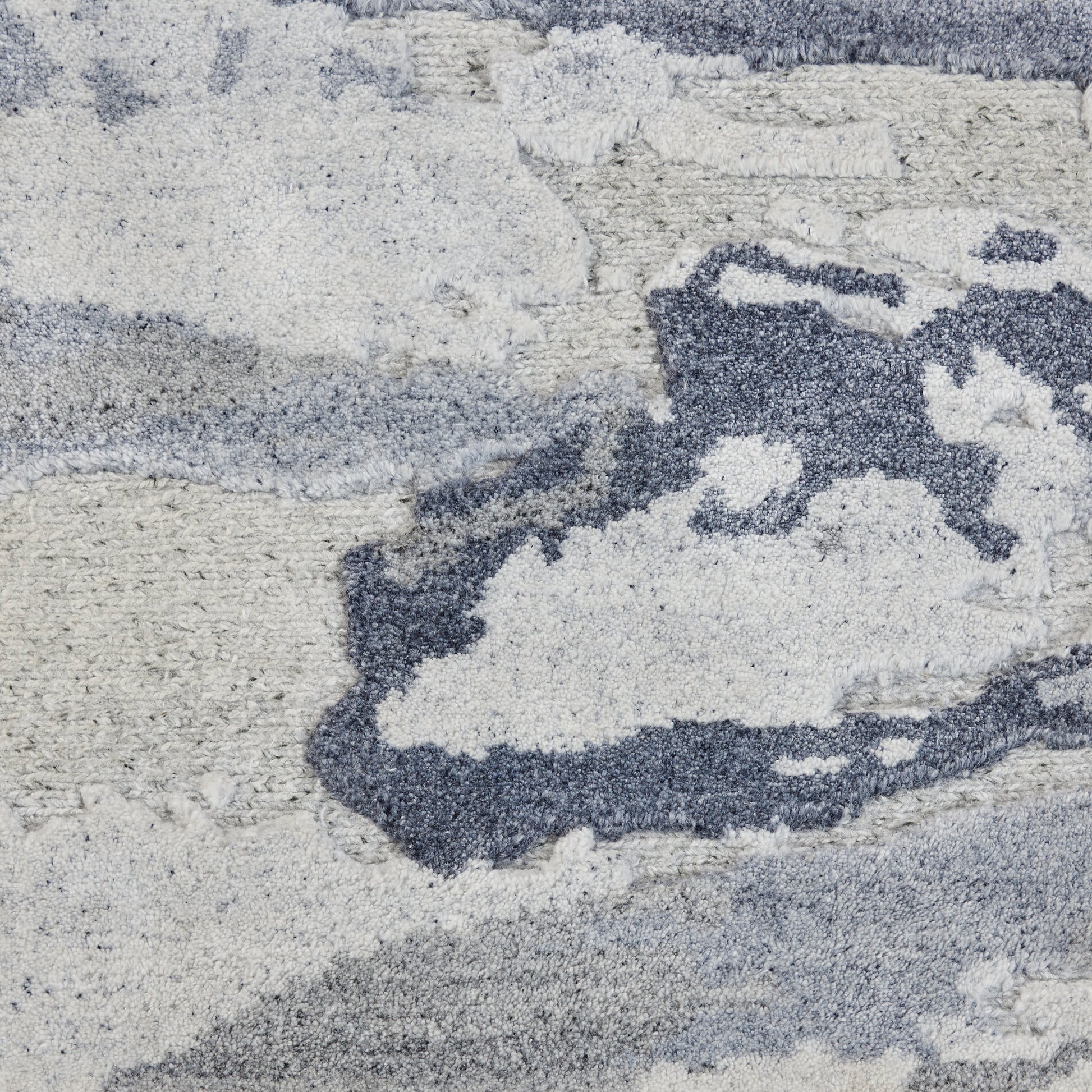 Abstract blue-gray and white rug close-up with plush shag pile and soft, textured surface.