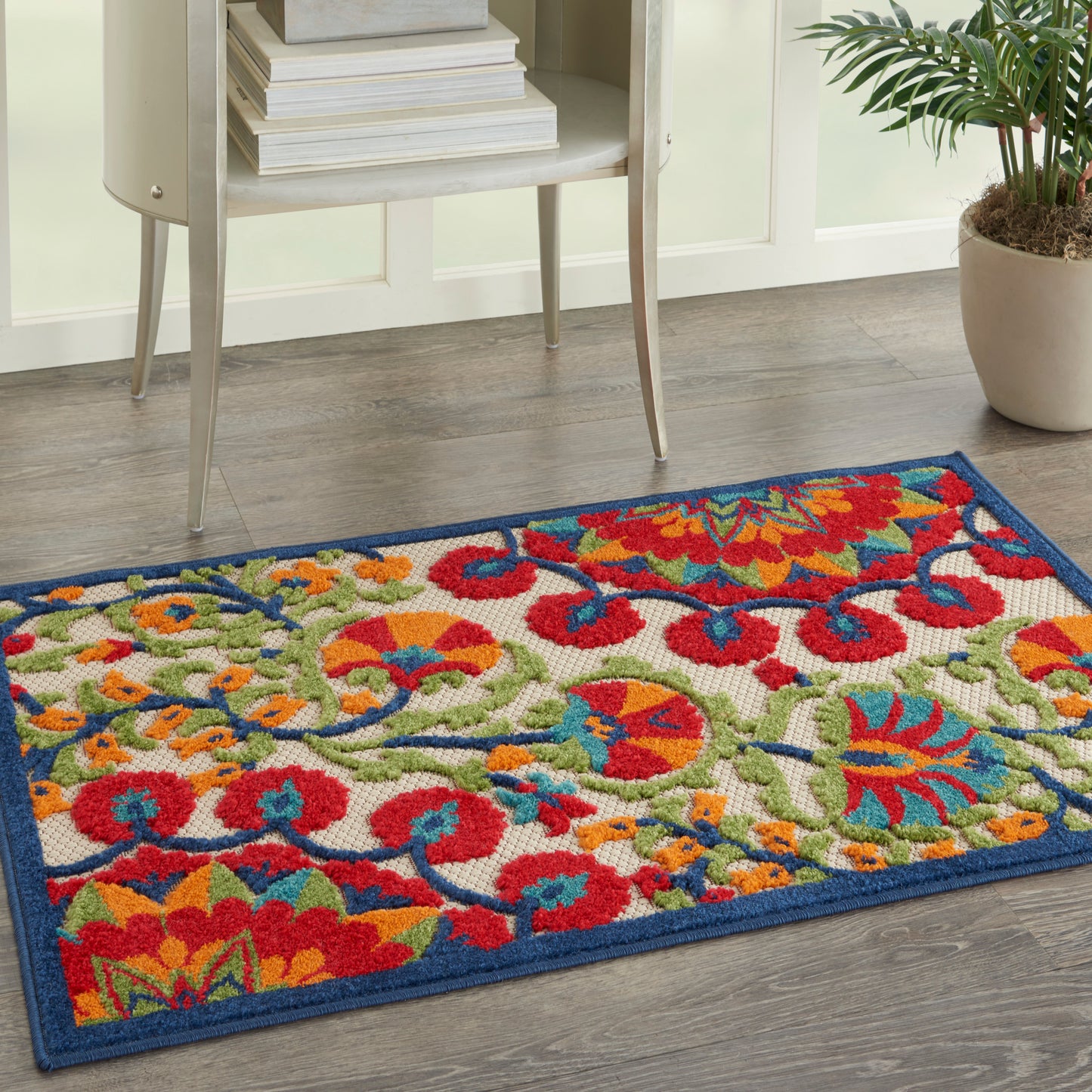 Vibrant floral rectangular rug with a dark blue border; red, orange, yellow and green blossoms, low-pile, entryway decor.