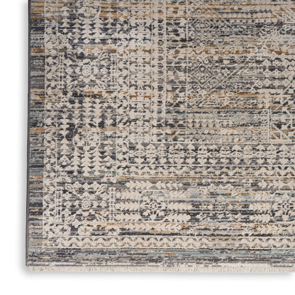 Distressed oriental-style rug in ivory, gray and tan with geometric patterns and a fringed edge.