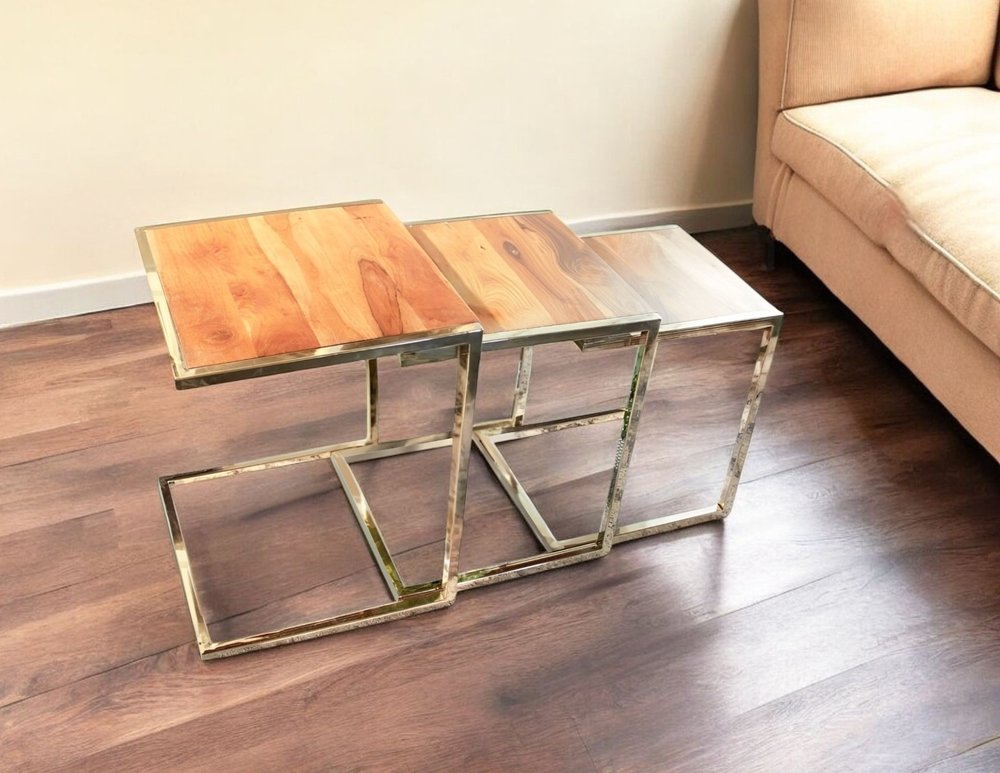Three C-shaped nesting end tables with light wood tops and metal frames on a dark wood floor.