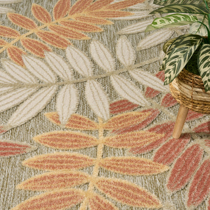 Boho rug with orange & cream leaf pattern on gray; potted plant in woven basket nearby.
