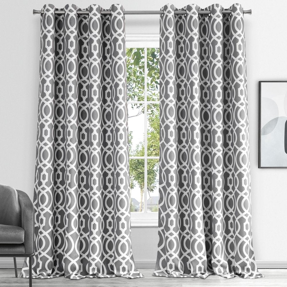 Gray geometric lattice patterned curtains hanging from a silver rod, floor-length in a bright living room.