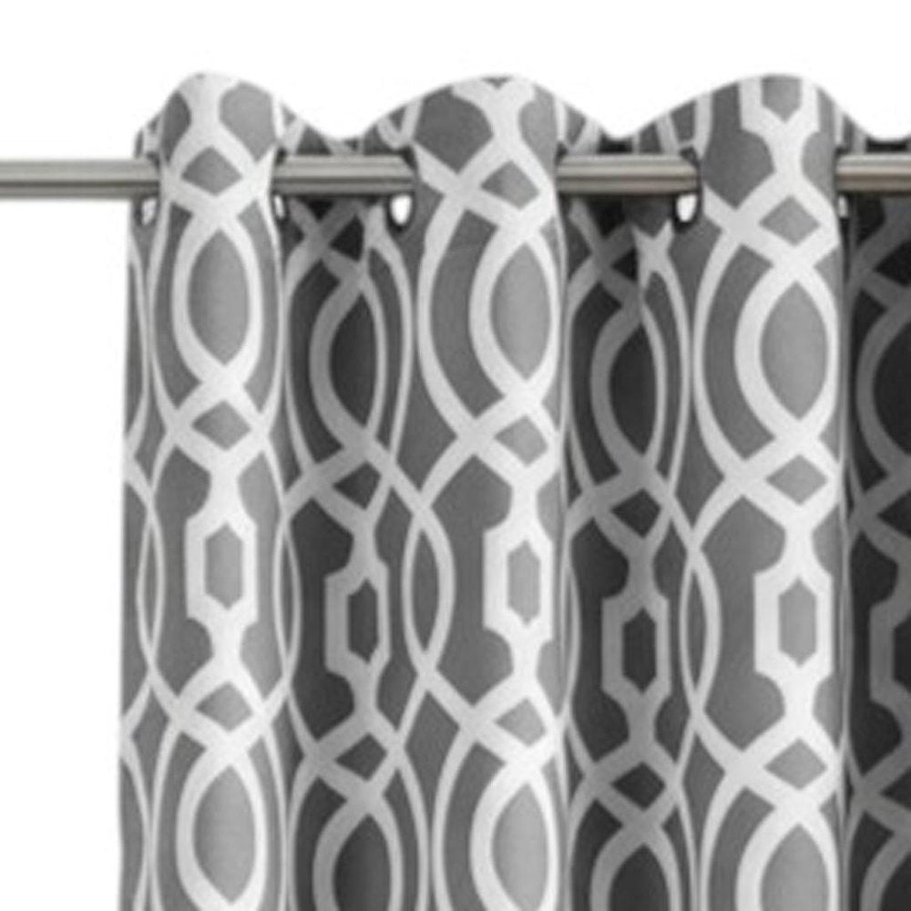 Grey & white geometric patterned curtain with interlocking shapes, hung on a metal rod with silver grommets.