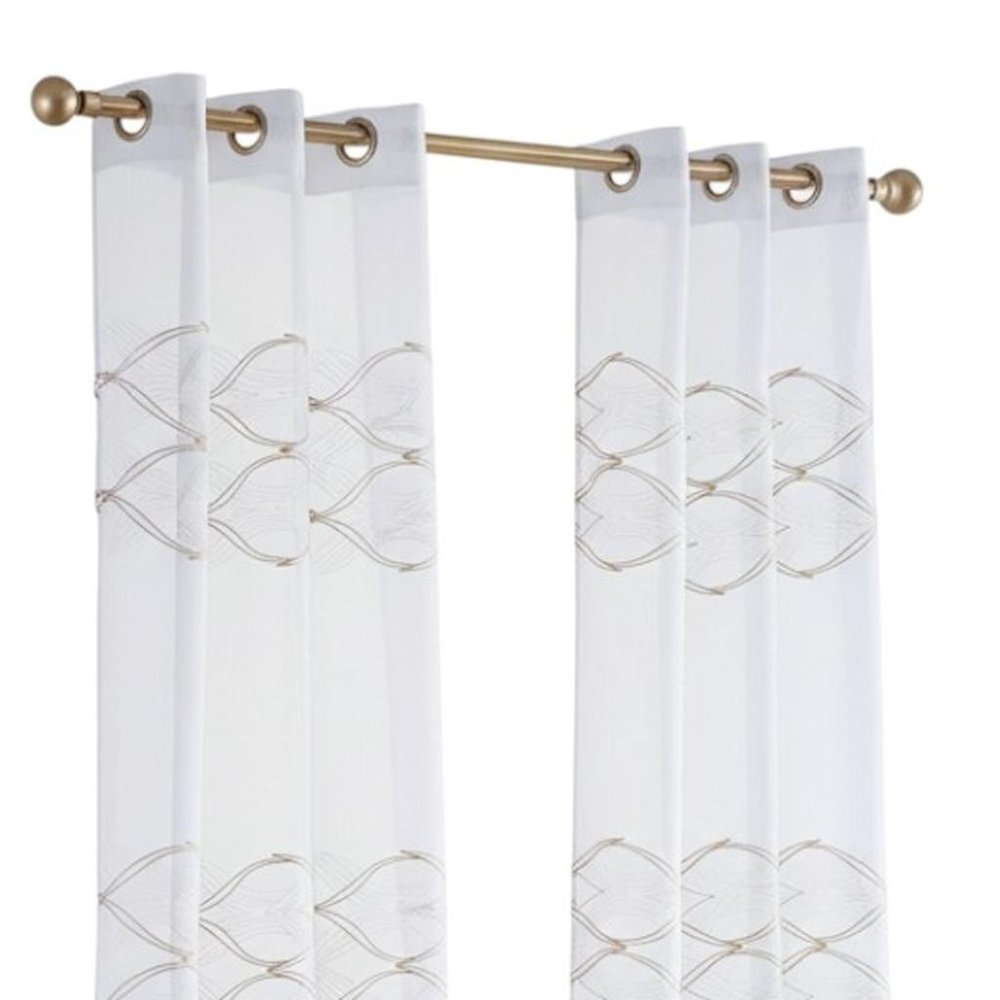 Two white sheer curtain panels with gold wave embroidery, hung on a brass-gold rod with round finials.