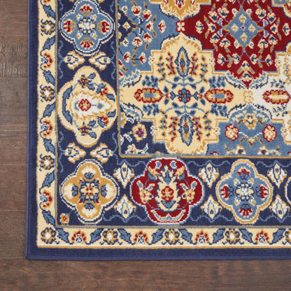 Rectangular Persian-style rug with blue, ivory, gold and red floral medallions on a dark border, laid on a wood floor.