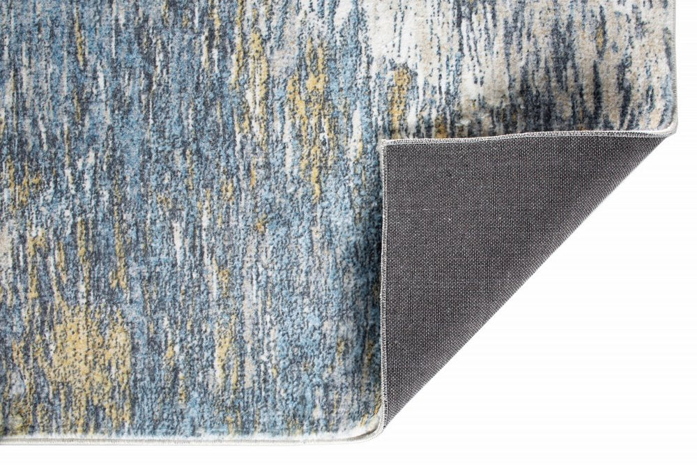 Abstract blue and gold low-pile area rug with white binding along edge; dark brown underside exposed.