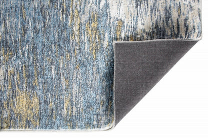 Abstract blue and gold low-pile area rug with white binding along edge; dark brown underside exposed.