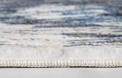 Close-up of a blue and gold abstract rug with a white fringe along the edge, modern decorative floor covering.