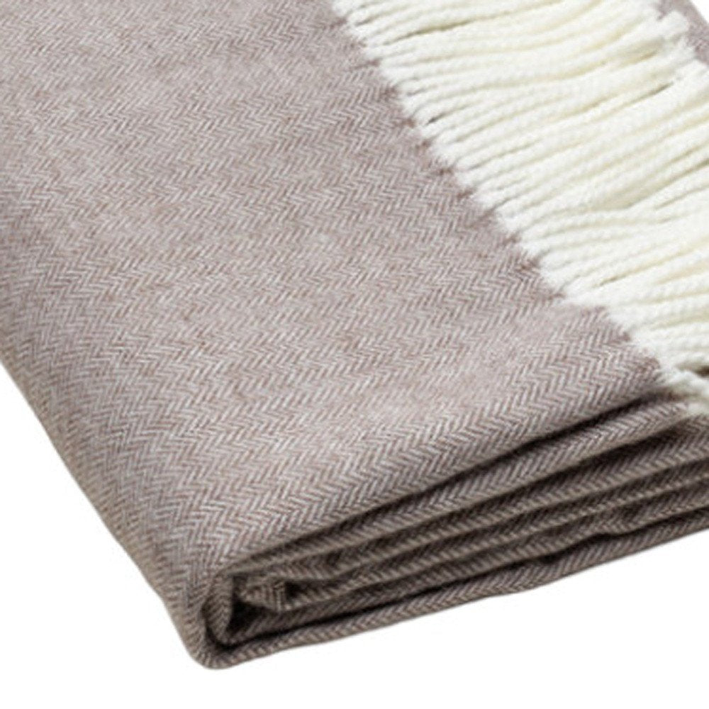 Beige herringbone throw blanket with cream fringe, folded for display.