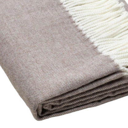 Beige herringbone throw blanket with cream fringe, folded for display.