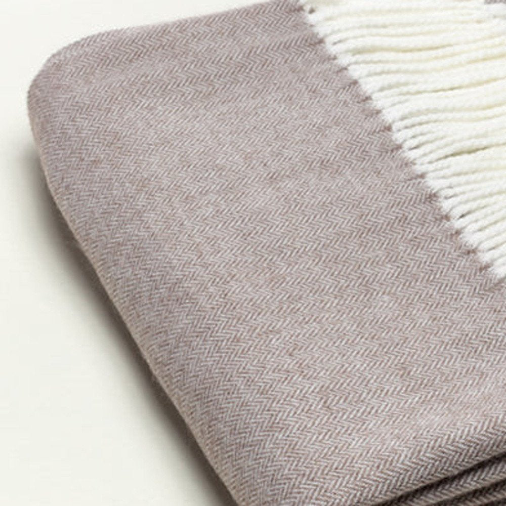 Taupe herringbone-knit scarf with white fringe, folded neatly.