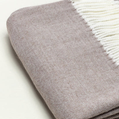 Taupe herringbone-knit scarf with white fringe, folded neatly.
