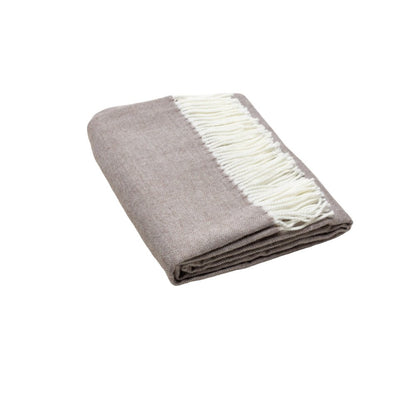Taupe throw blanket with white fringe, folded to showcase soft knit for cozy home decor.