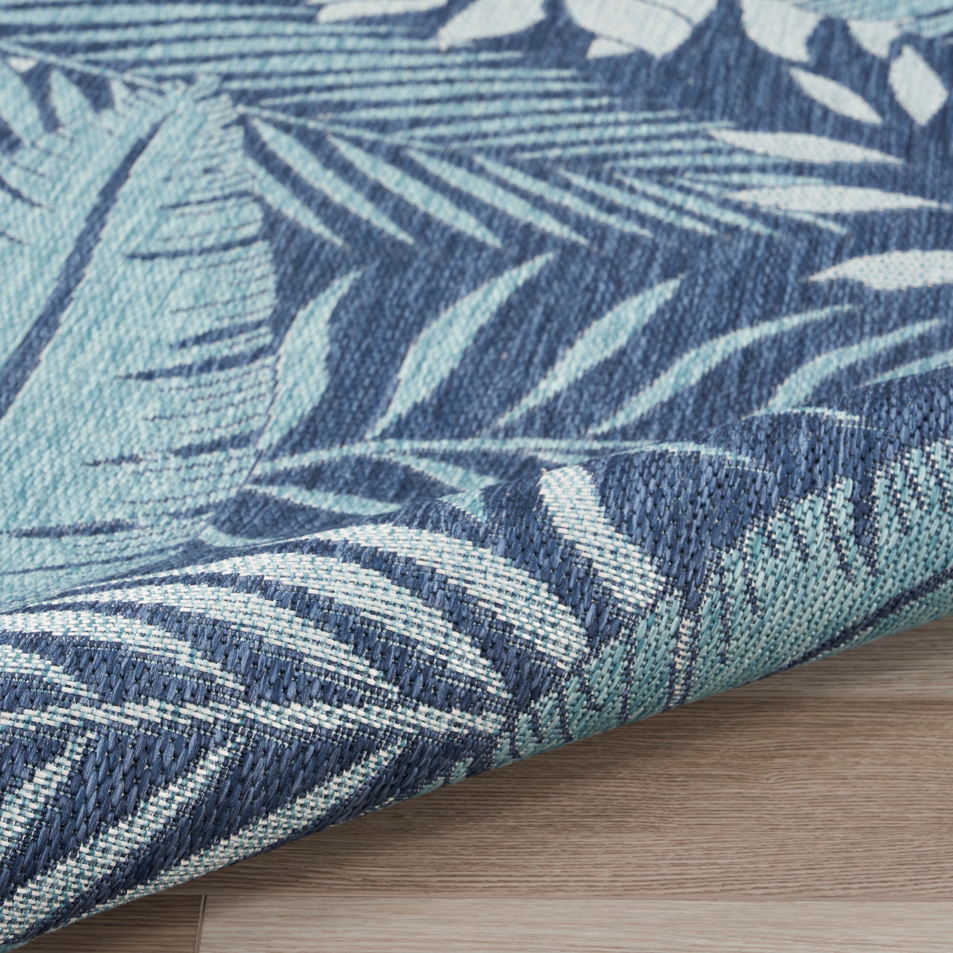 Blue and teal palm-leaf patterned woven rug; tropical style, dense weave, decorative rug.