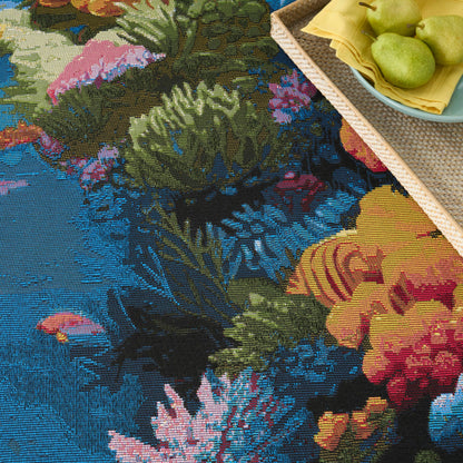Colorful floral tapestry rug with blue backdrop, woven texture; basket of pears on a yellow napkin beside it.
