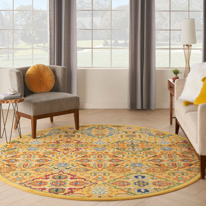 Round colorful rug with yellow border in a living room; gray chair with orange pillow and beige sofa with yellow cushions.