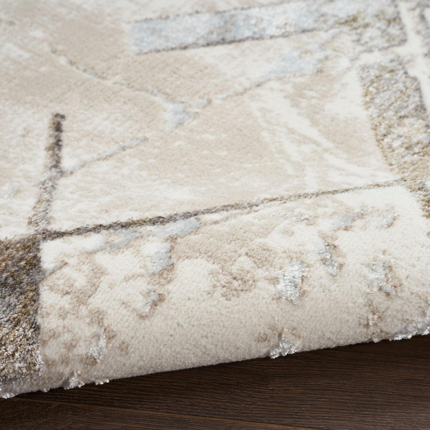 Rectangular beige area rug with cream and brown abstract geometric pattern and plush texture.