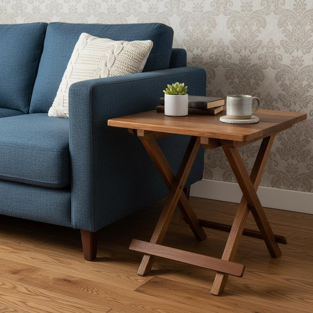 Blue fabric sofa with beige knit cushion beside a wooden X-leg side table holding books, a mug, and a succulent.