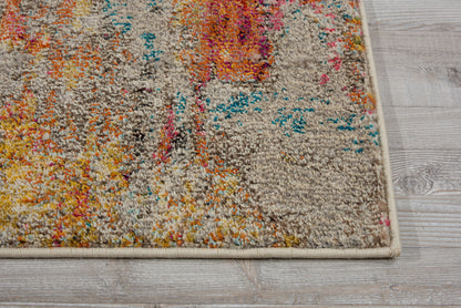 Rectangular tufted area rug with beige base and vibrant abstract pattern in orange, pink, blue and yellow on a light wood floor.