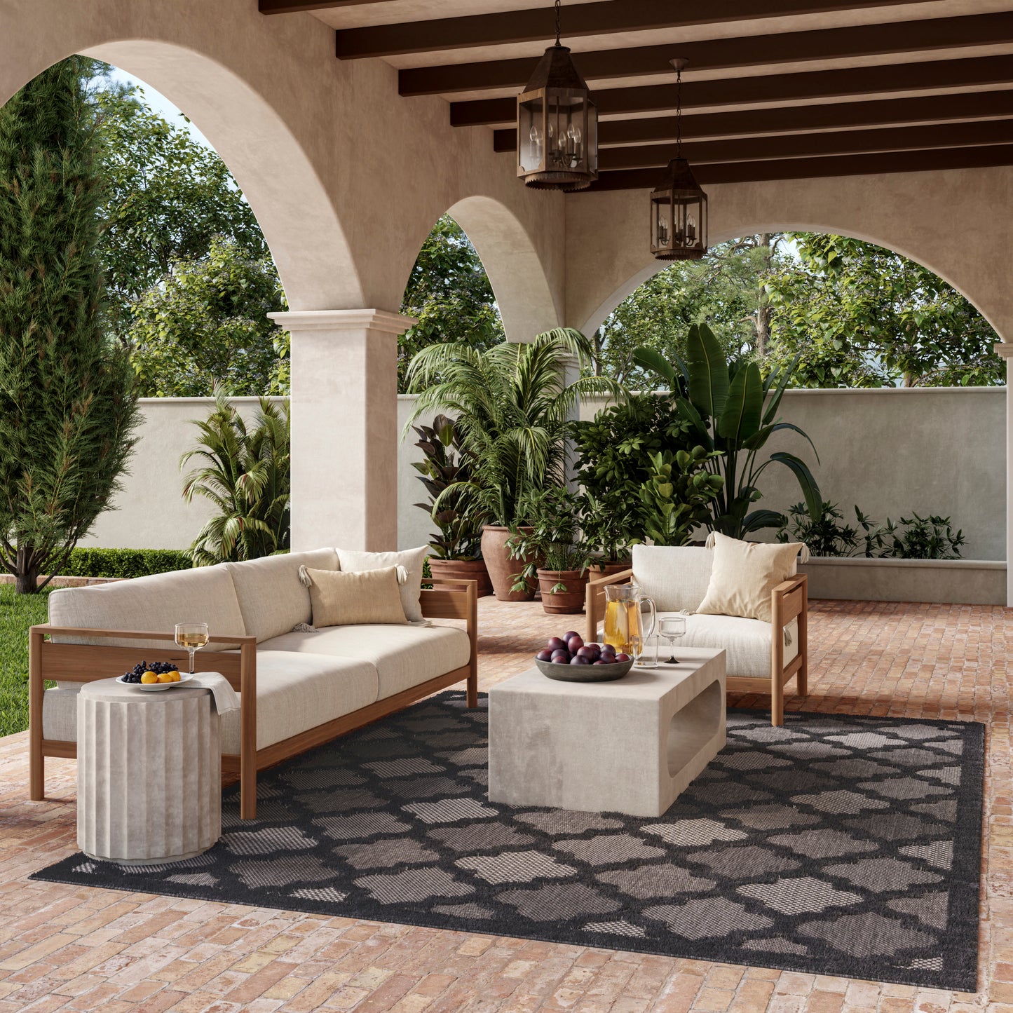 Outdoor patio with beige cushioned wooden sofas, concrete coffee table, dark patterned rug, arches, and hanging lanterns.