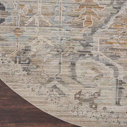 Distressed vintage-style round rug with muted beige, ivory, gray and blue floral motifs; wood floor edge visible.