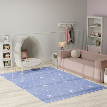 Pastel kids space: pink velvet sofa, grey cocoon chair, blue diamond rug, white shelves, light wood floor.