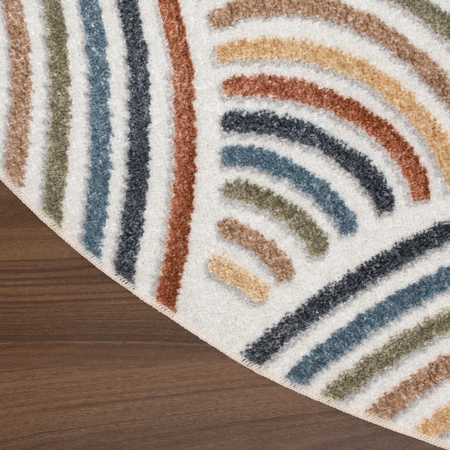 Round shag rug with multicolor curved stripe pattern on cream background, placed on wood floor.