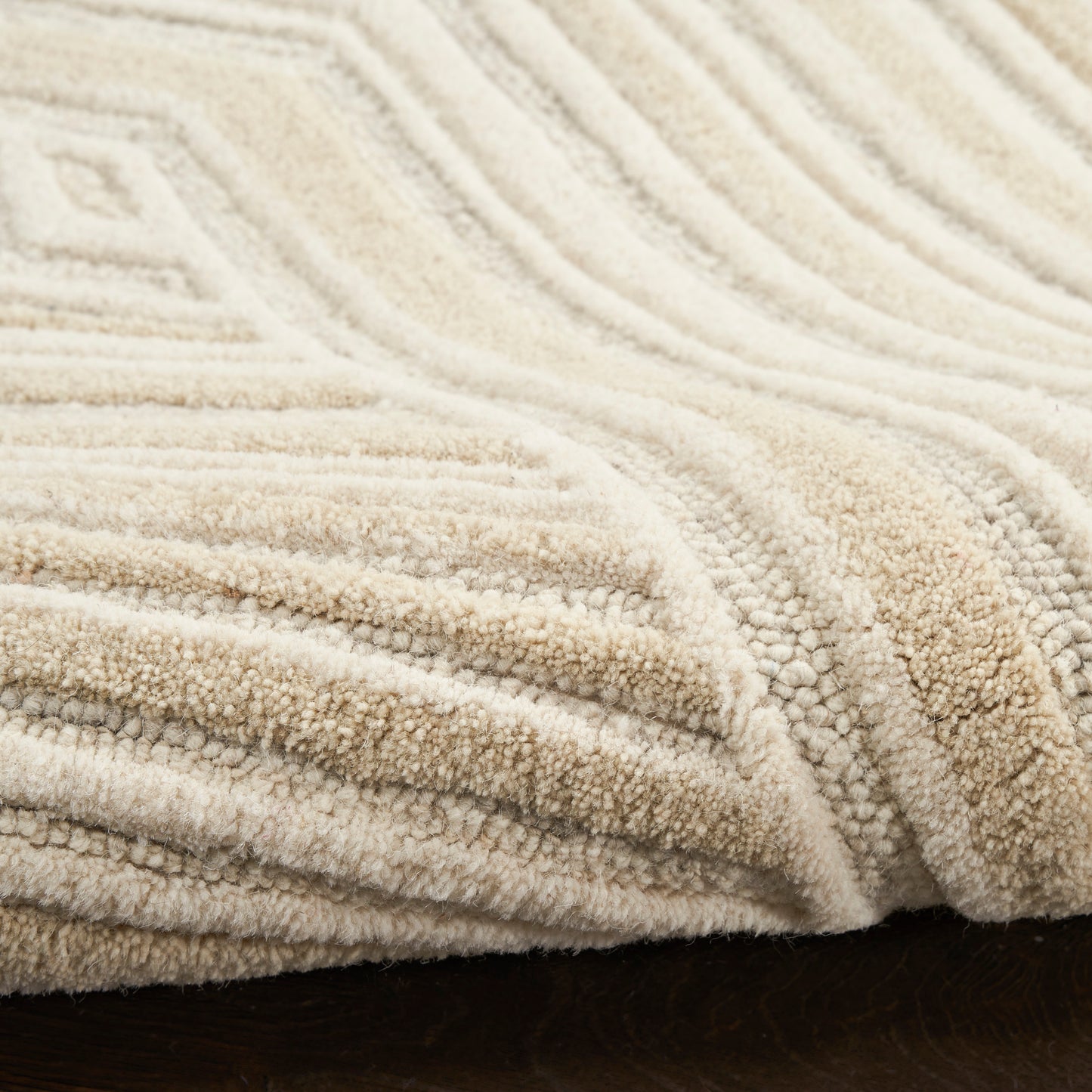 Cream beige plush shag rug with a thick, soft pile and raised geometric diamond pattern on dark wood flooring.