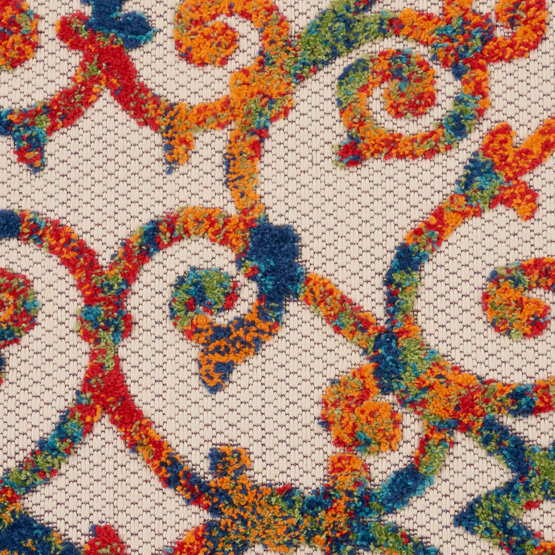 Close-up of multicolor embroidered scrollwork on beige mesh lace; vibrant orange, red, blue, green floral vines.