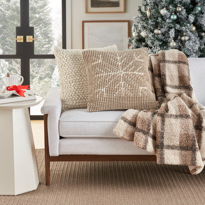 Beige ivory decorative pillow (20" x 20") on a gray sofa, flanked by a chunky cream knit pillow and a taupe patterned pillow, with a plaid throw, beige rug and a Christmas tree in a cozy living room.