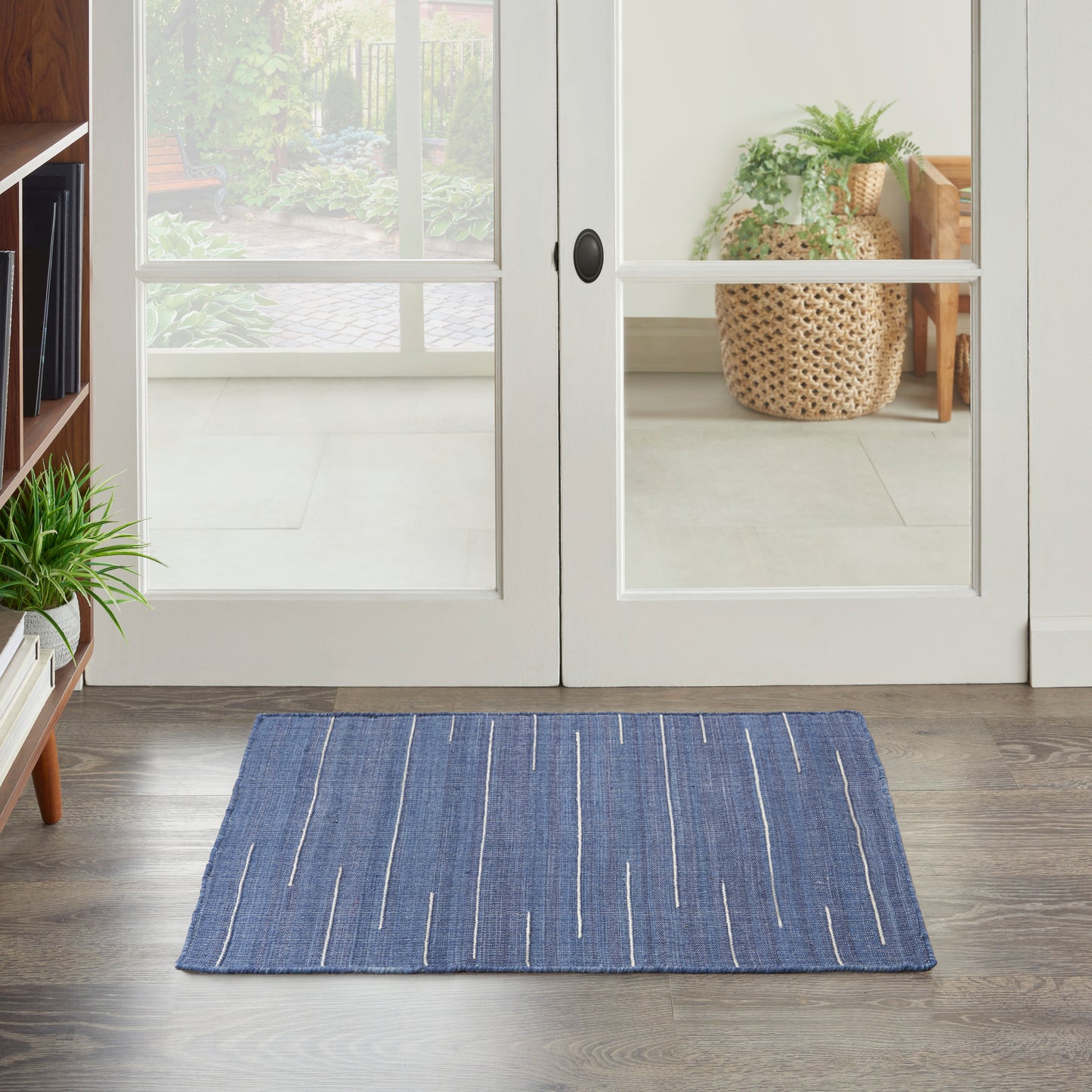 Blue woven rectangular rug with white linear stripes on a dark wood floor.