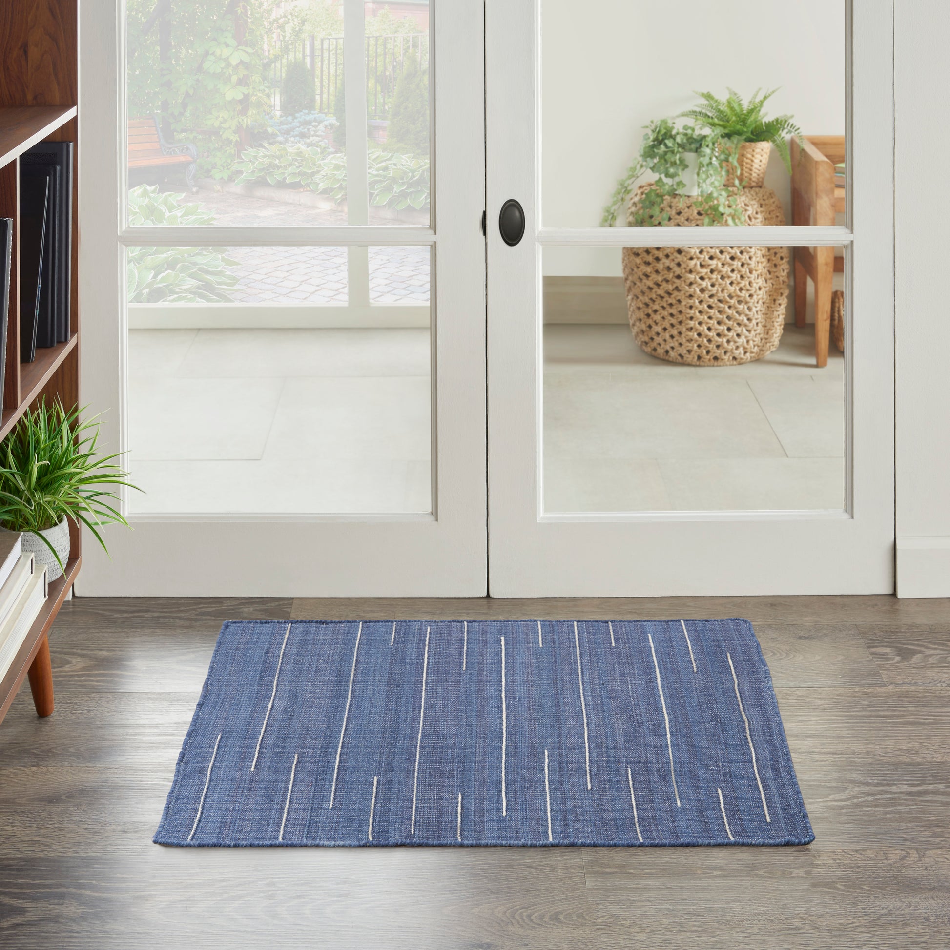 Blue woven rectangular rug with white linear stripes on a dark wood floor.