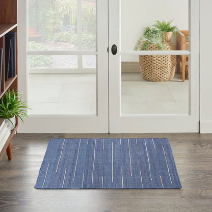 Blue woven rectangular rug with white linear stripes on a dark wood floor.