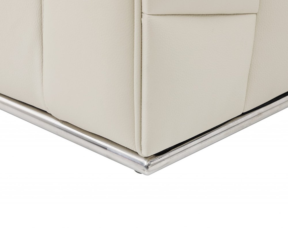 Cream leather sofa corner with chrome metal base trim and visible seam.