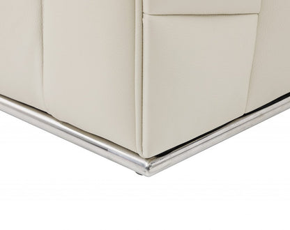 Cream leather sofa corner with chrome metal base trim and visible seam.