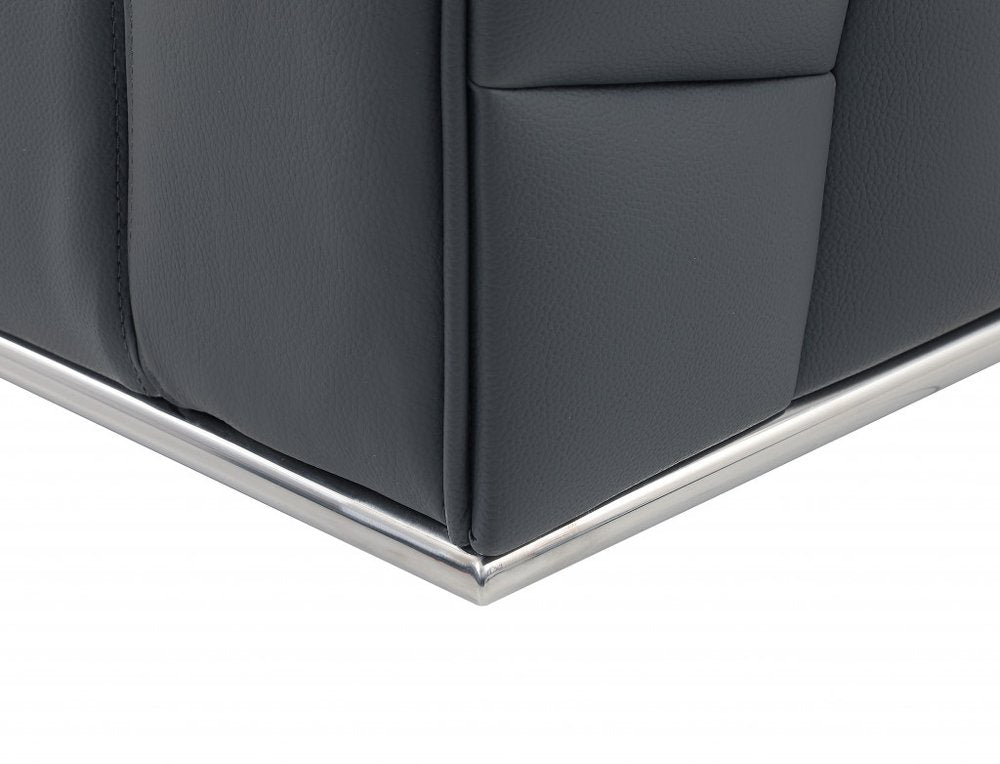 Close-up of dark gray leather corner panel on a sofa with chrome metal trim along the base.