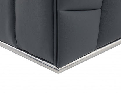 Close-up of dark gray leather corner panel on a sofa with chrome metal trim along the base.