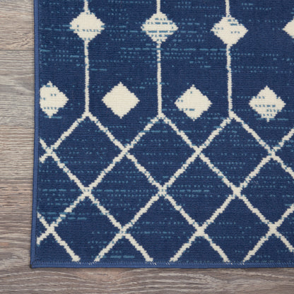 Navy blue woven rug with white diamond lattice pattern; geometric modern style, border edge on wood floor.