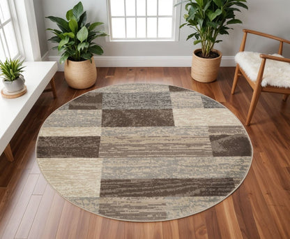 Round patchwork rug in beige, gray and taupe tones on a wood floor, airy living room with potted plants and a wooden chair.