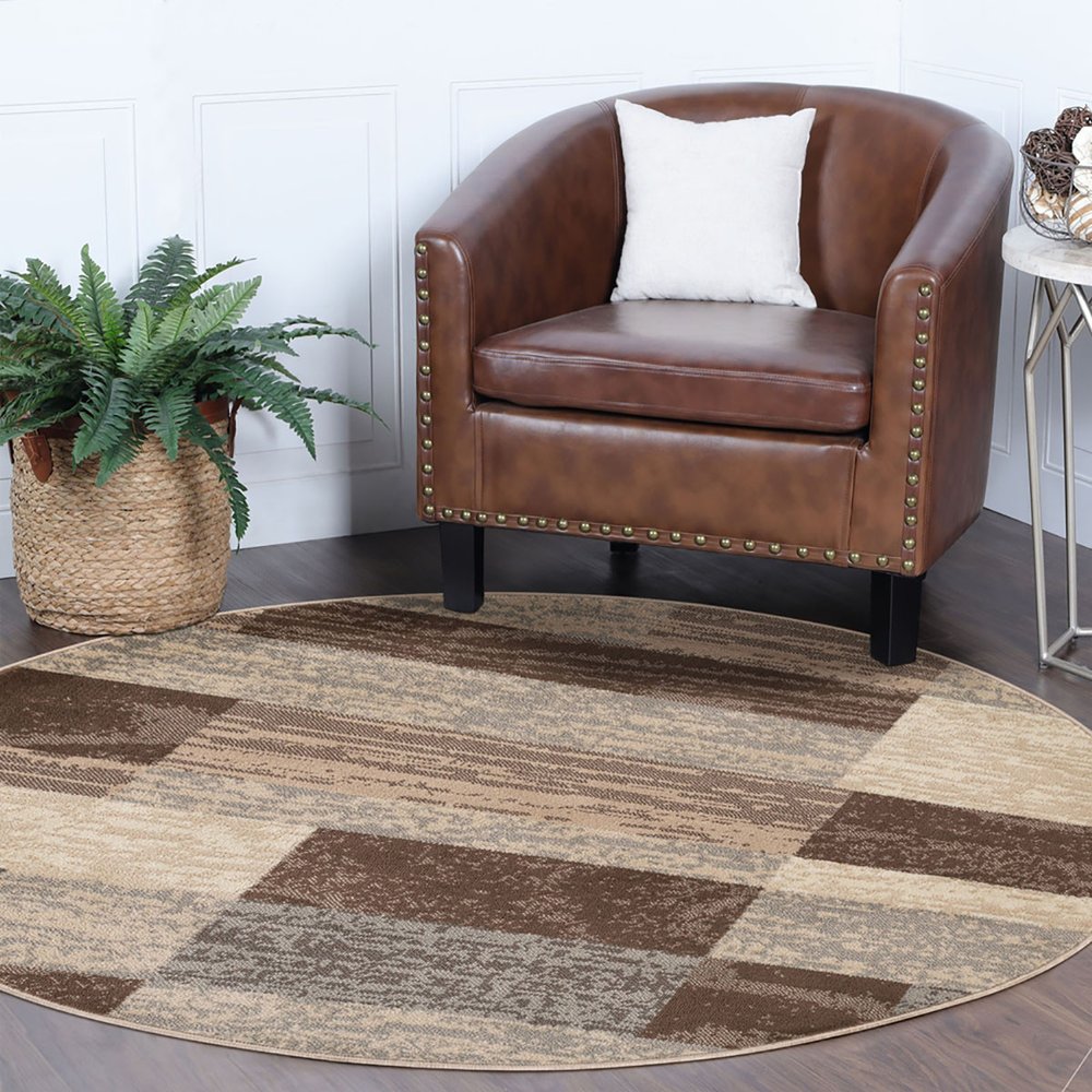 8' round patchwork rug in beige, slate gray and brown; visible decor includes a potted fern and side table.